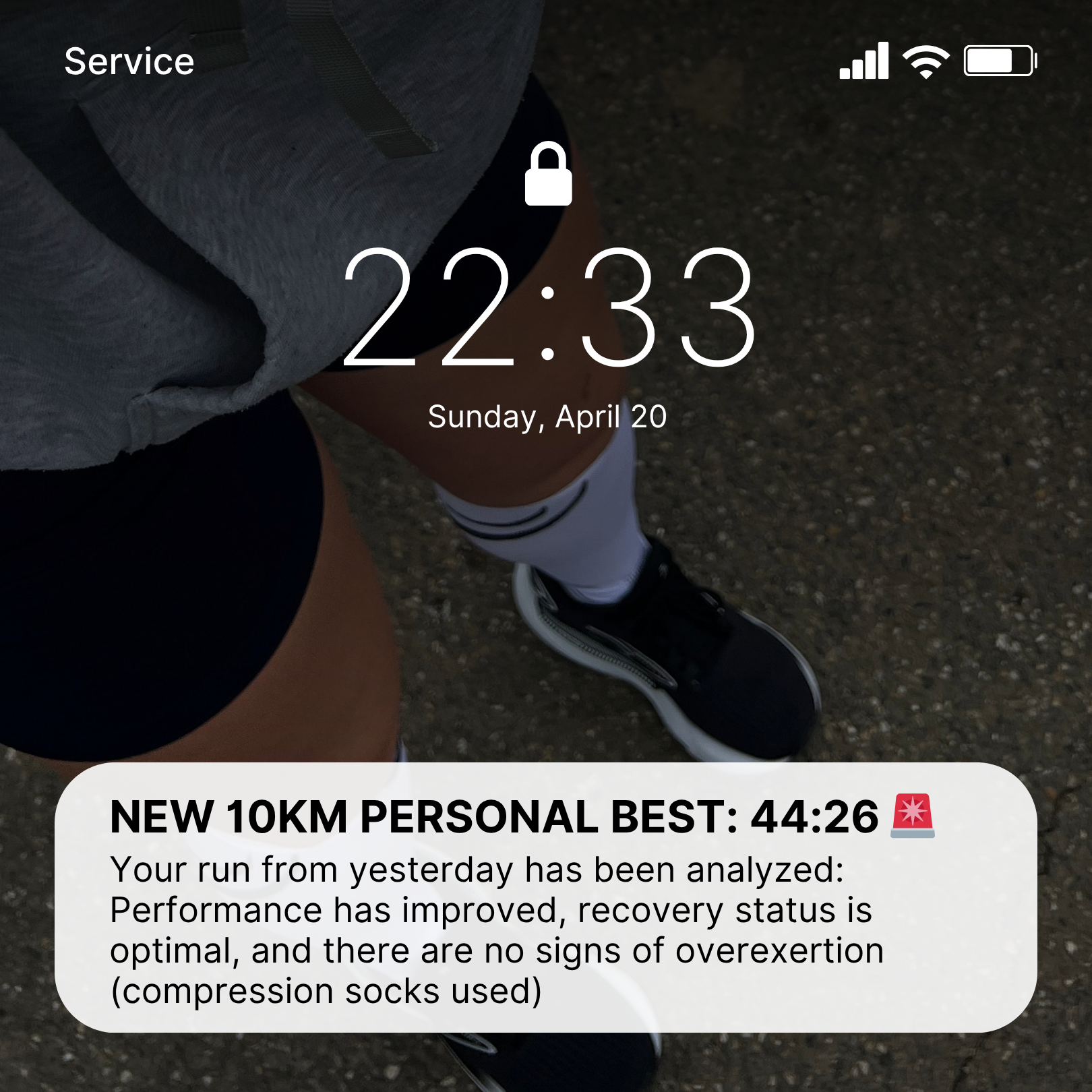 Phone screen showing a lock icon with time and date, and a text notification about a 10km personal best.